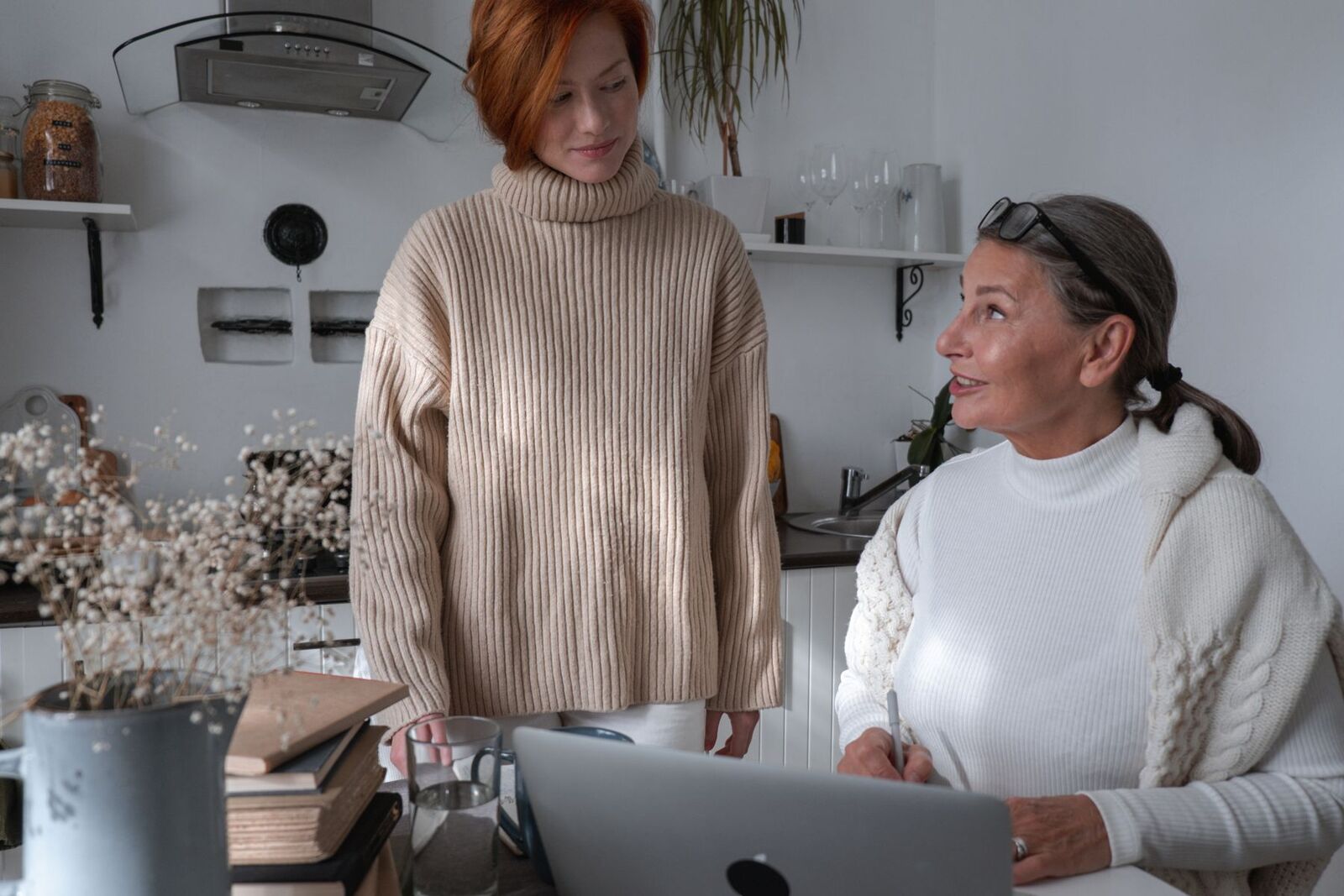 Two women talking together over a laptop at a kitchen table