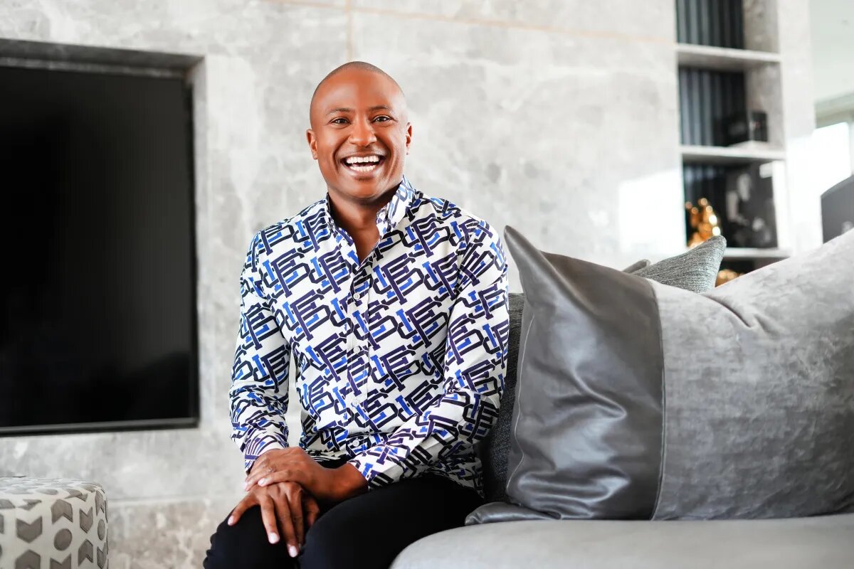 MJ Harris smiling while seated in a patterned shirt